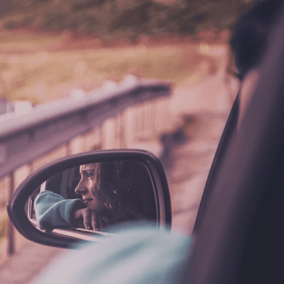 Mulher olhando para fora do carro, ângulo através do retrovisor.