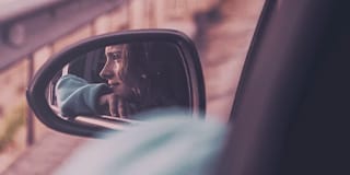 Mulher olhando para fora do carro, ângulo através do retrovisor.